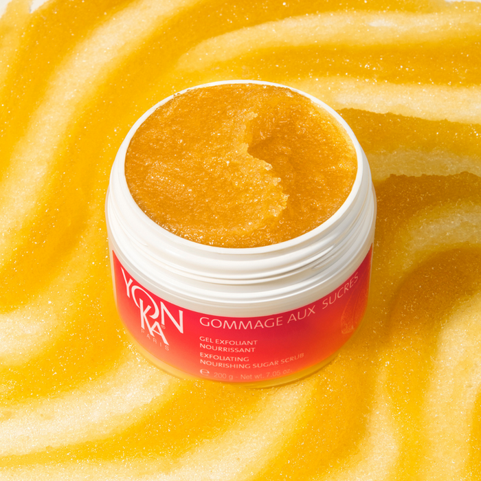 Open jar of Gommage Sucre Mandarin Body Scrub | Yon-Ka Paris displaying golden exfoliating sugar scrub on a matching textured yellow background for skincare and body care.