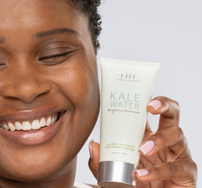Smiling person holding a tube of Kale Water Weightless Moisturizer | Farmhouse Fresh, showcasing skincare product for lightweight, oil-free hydration with a fresh matte finish.