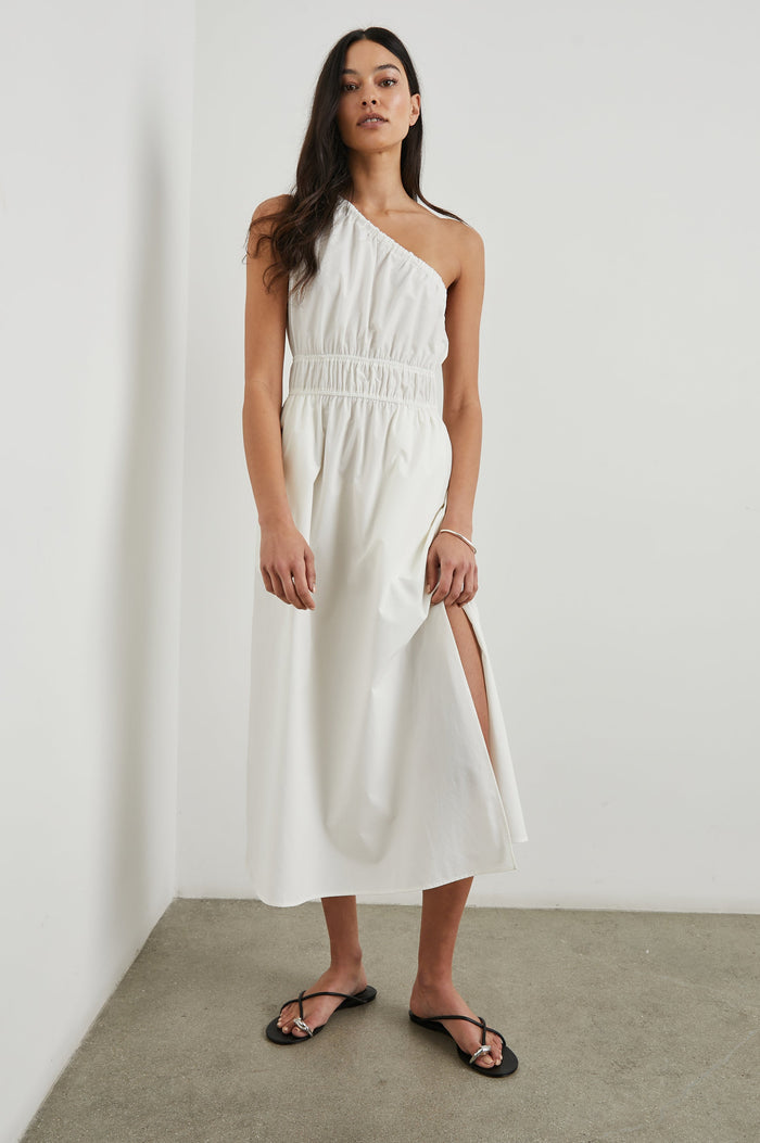 Selani Midi Dress With an Asymmetrical Neckline, Mid-Thigh Slide Slit and Cinched Waistband in White Colorway - Front Full Body View Featured on Model