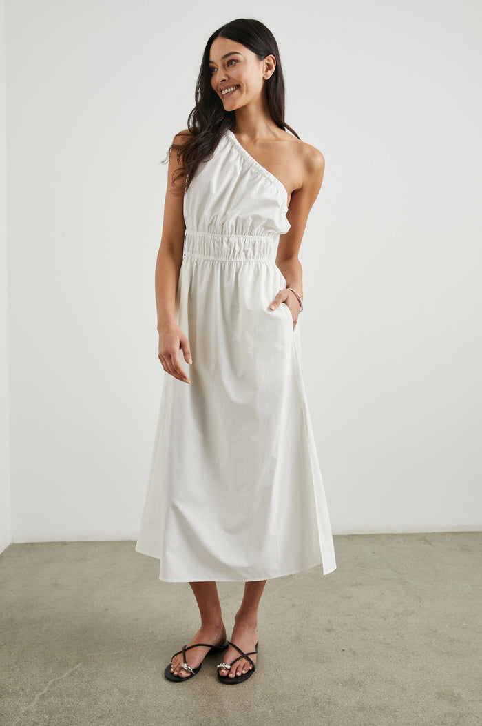 Selani Midi Dress With an Asymmetrical Neckline, Mid-Thigh Slide Slit and Cinched Waistband in White Colorway - Front Full Body View Featured on Model